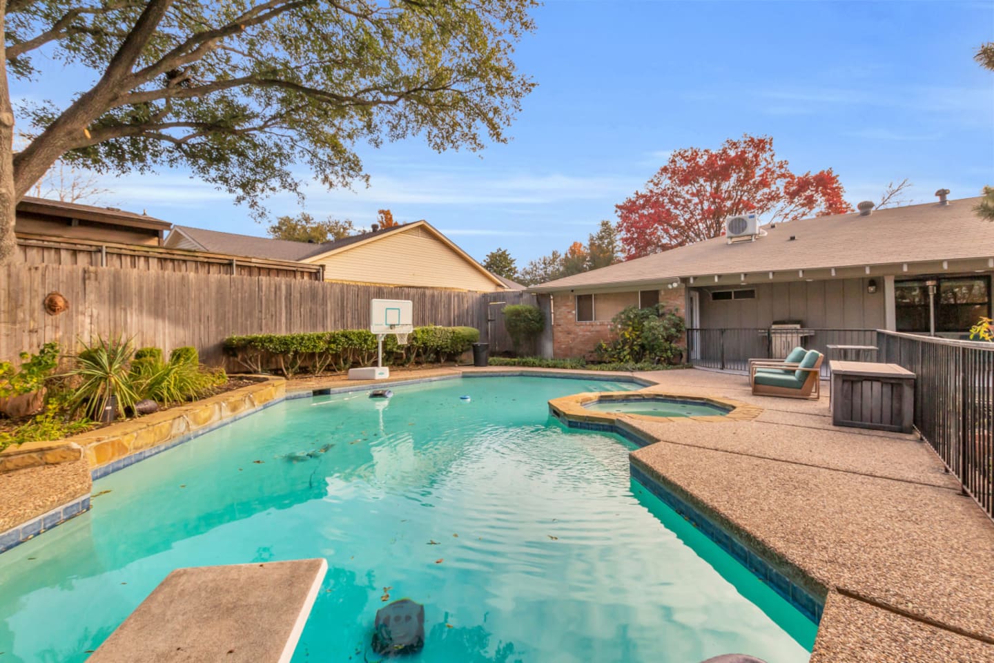 Expansive private pool with a diving board and basketball pool hoop, creating a fun, resort-style space for swimming, games, and outdoor enjoyment.