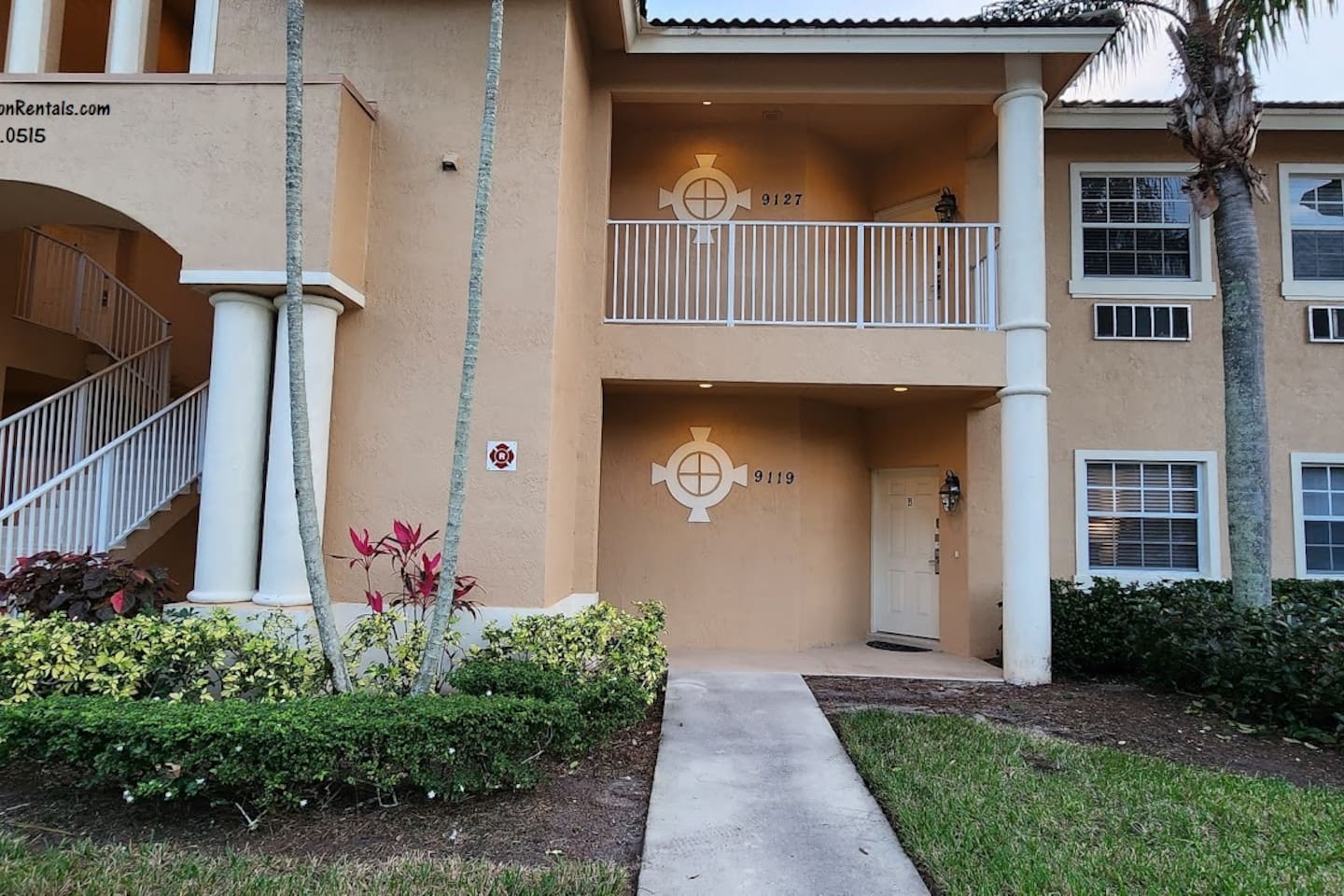 Exterior view of the building with covered entryways, tropical landscaping, and Florida-style architecture.