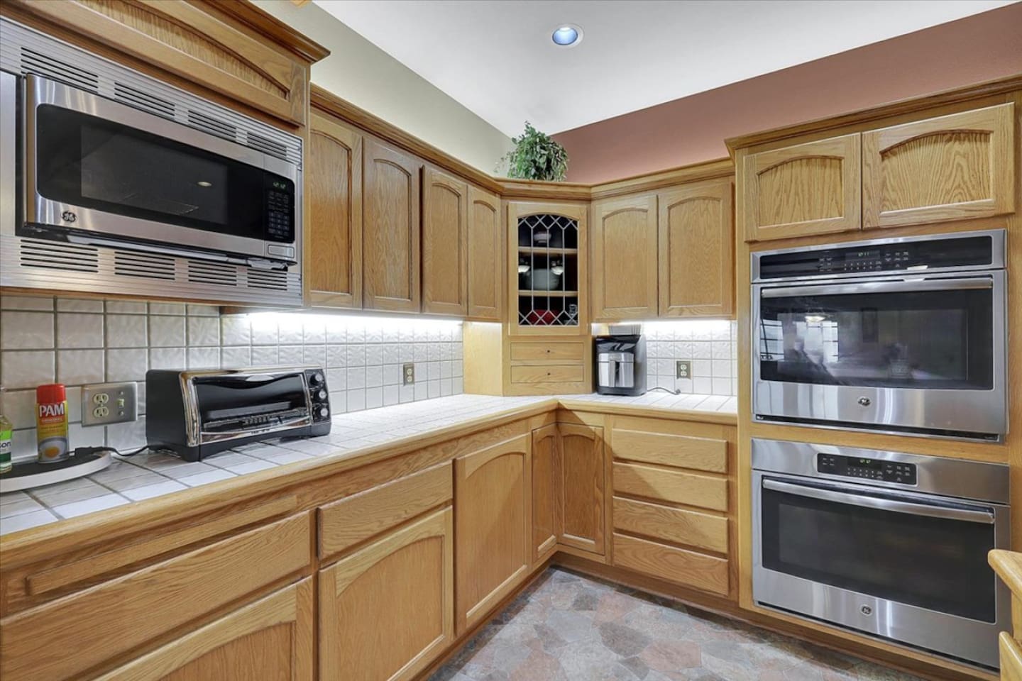 Kitchen counter area with microwave, toaster oven, coffee maker, and cabinet storage.
