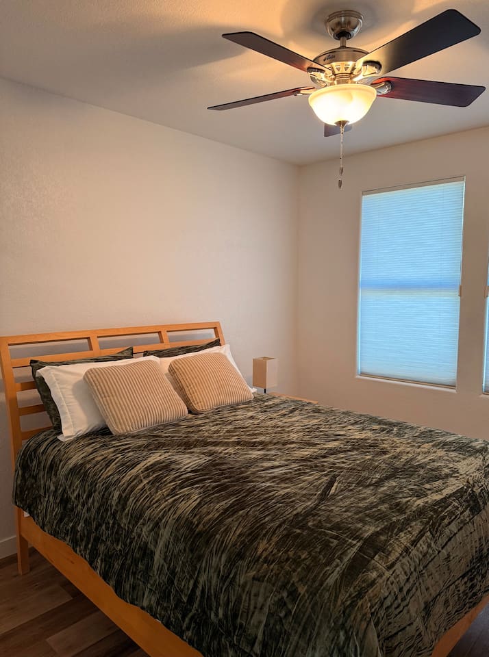 Queen bedroom with dresser storage, ceiling fan, and natural light for a comfortable stay.