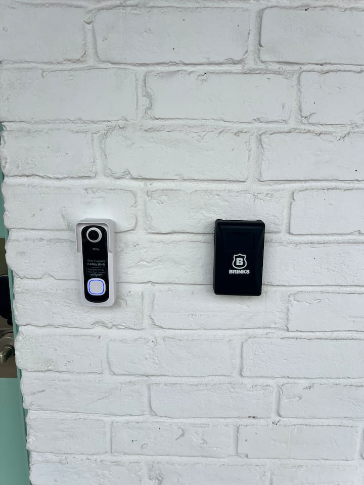 Entry detail with doorbell camera and Brinks access panel beside the front door.

