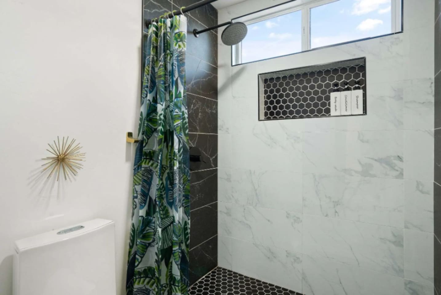 Bright bathroom with marble tile, walk-in shower, decorative accents, and modern fixtures.
