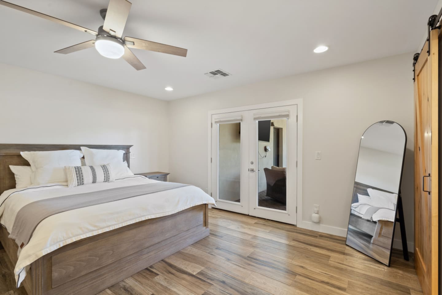 Main ensuite bedroom with queen bed, mirror, clean bedding, storage, and a simple restful layout.