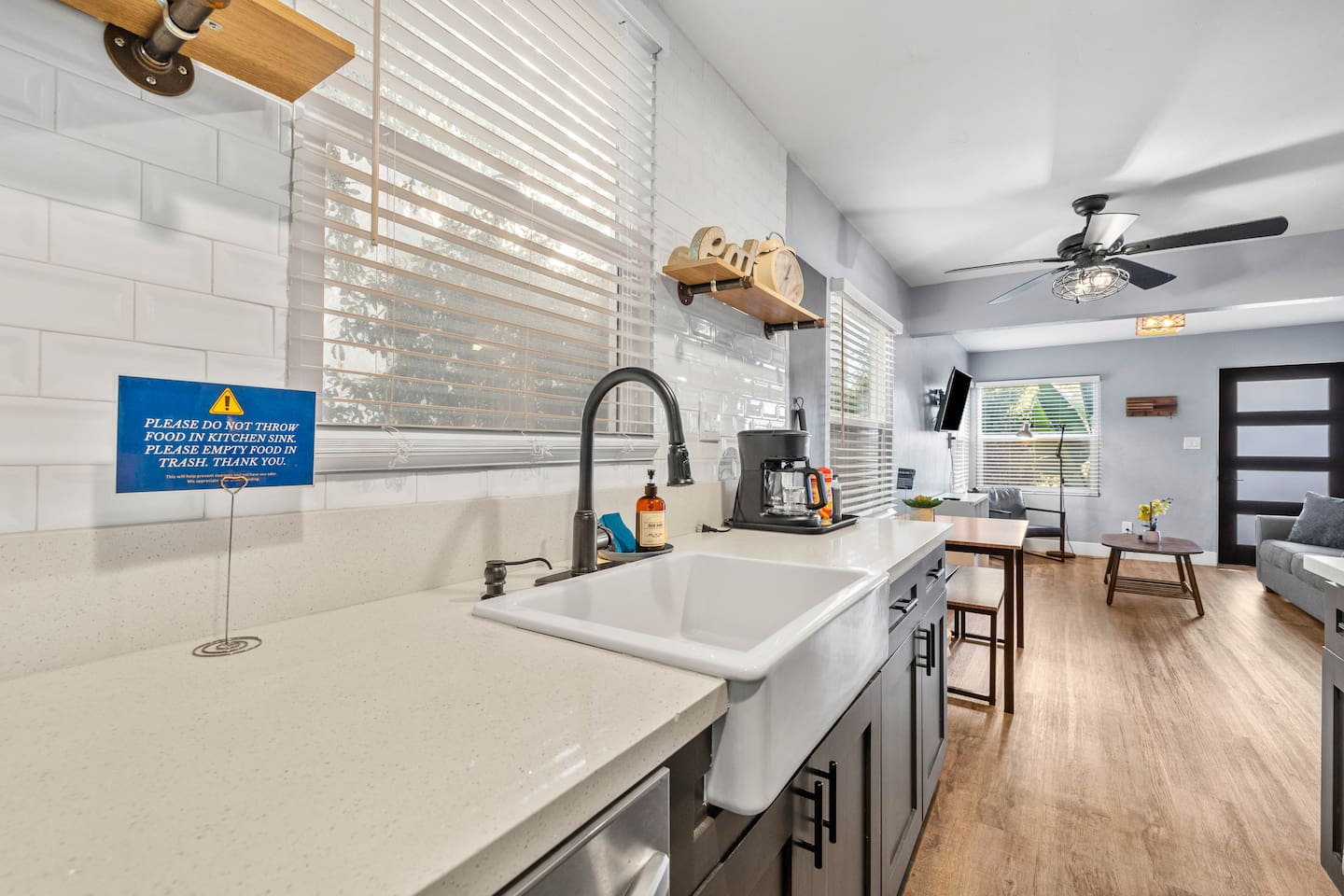Discover our spacious kitchen with a sleek sink, stove with microwave, and modern refrigerator. The open layout seamlessly connects to the cozy dining table and inviting living room, creating the perfect space for cooking, dining, and relaxation duri