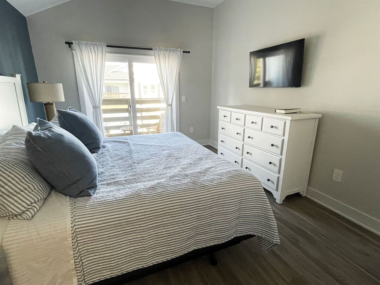 Another look at the serene primary bedroom showcasing ample storage, natural light, and wall-mounted TV for added comfort.