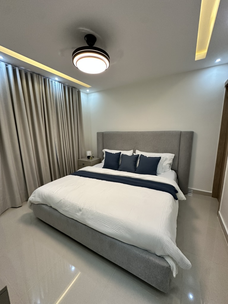 Spacious primary bedroom with a king bed, A/C, ceiling fan, TV, and vanity/workspace. 🛏️✨