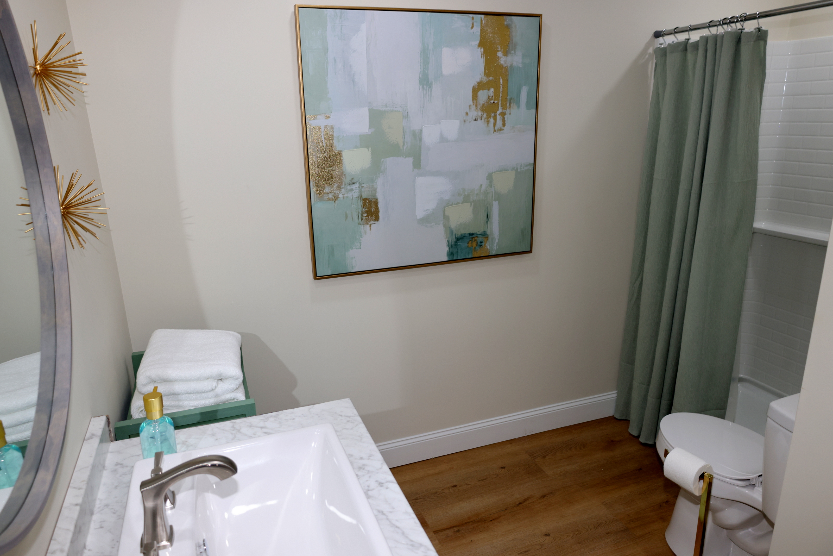 Clean, stylish bathroom with modern vanity, shower area, and soft green accents