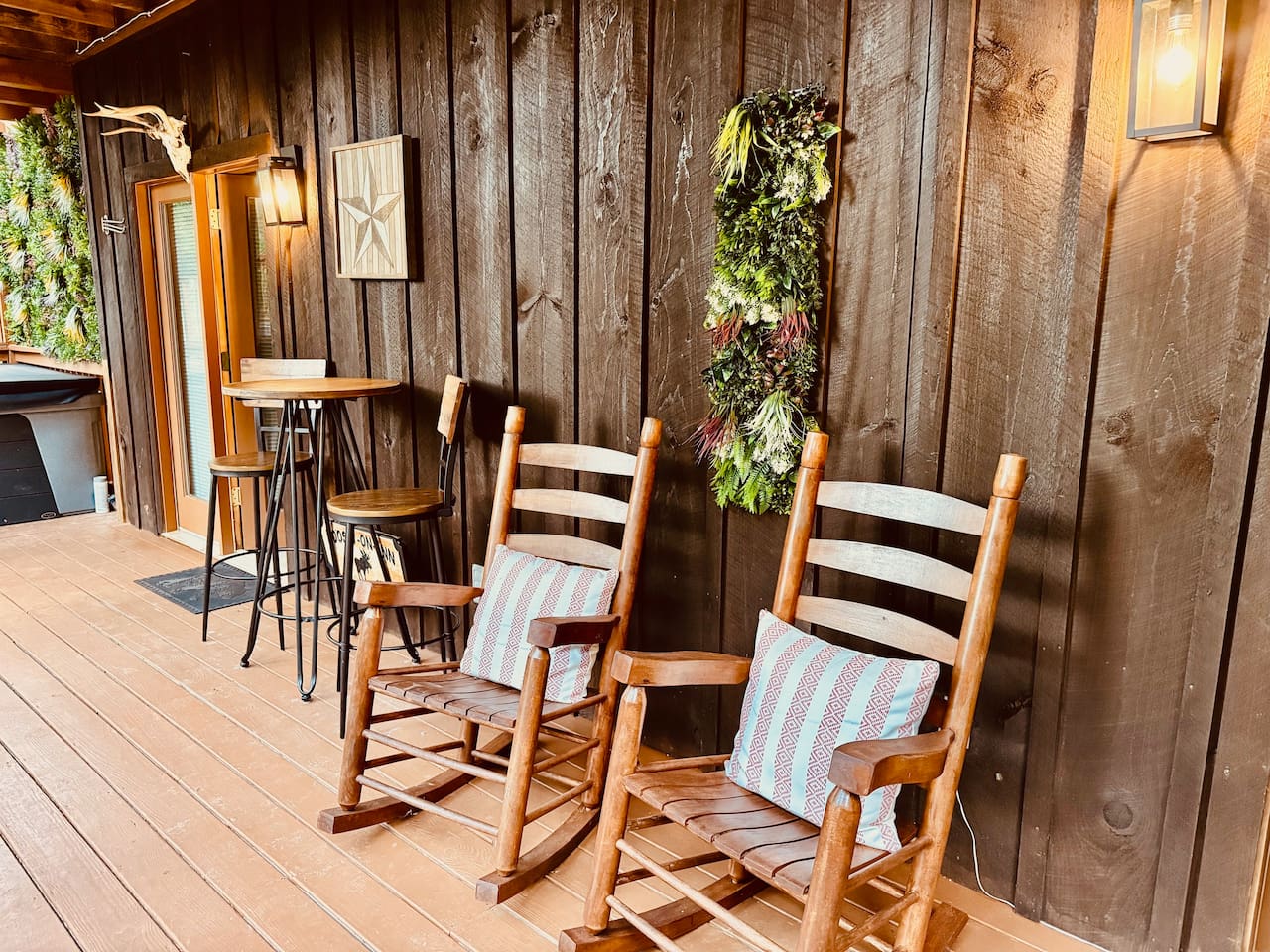 Cozy porch with rocking chairs, bistro table, and greenery wreath.