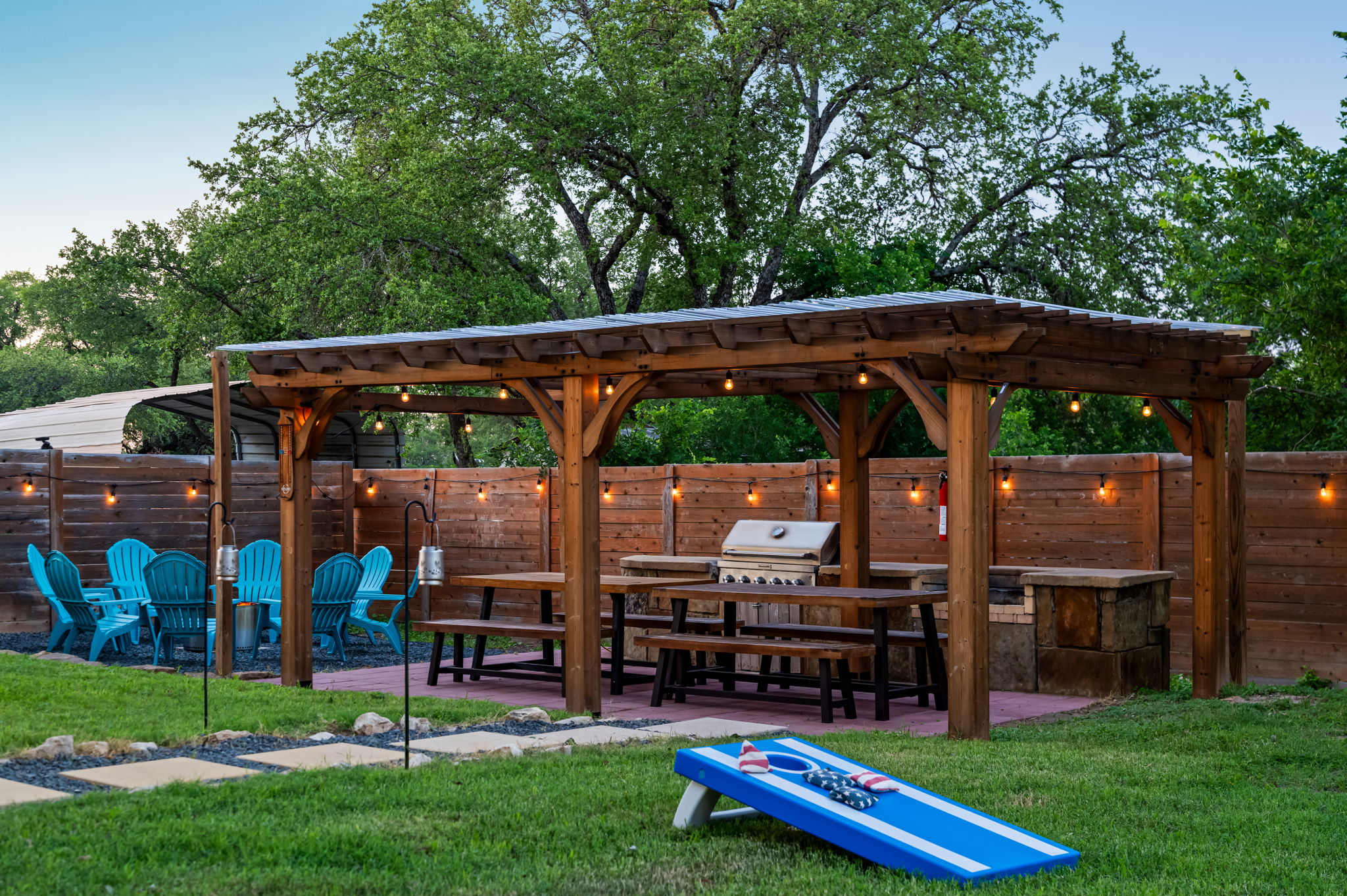Enjoy the ultimate backyard setup with a covered BBQ pavilion, outdoor dining, fire pit seating, and lawn games. Perfect for cookouts, family gatherings, and relaxing evenings under the string lights.