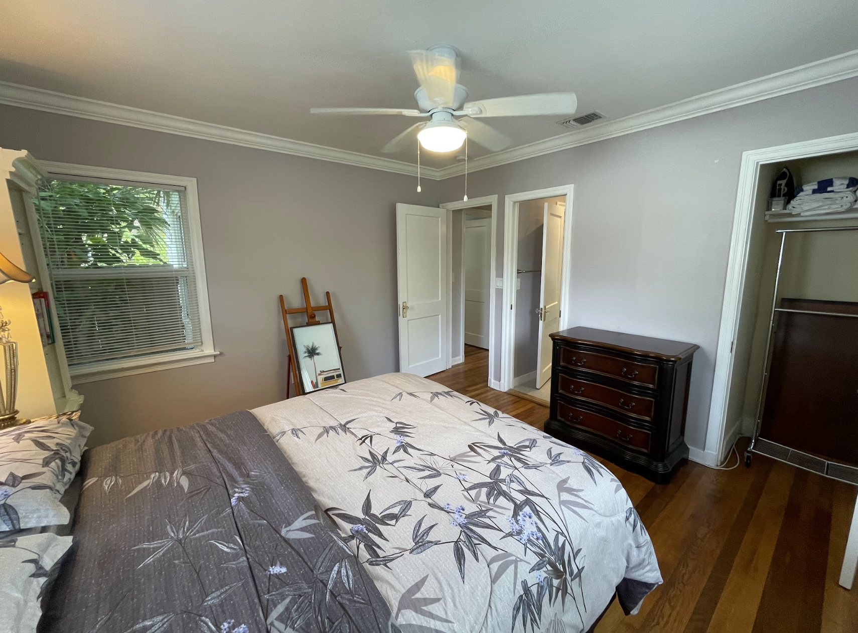 The second bedroom features a queen-zied bed and a stylish painter's floor stand.