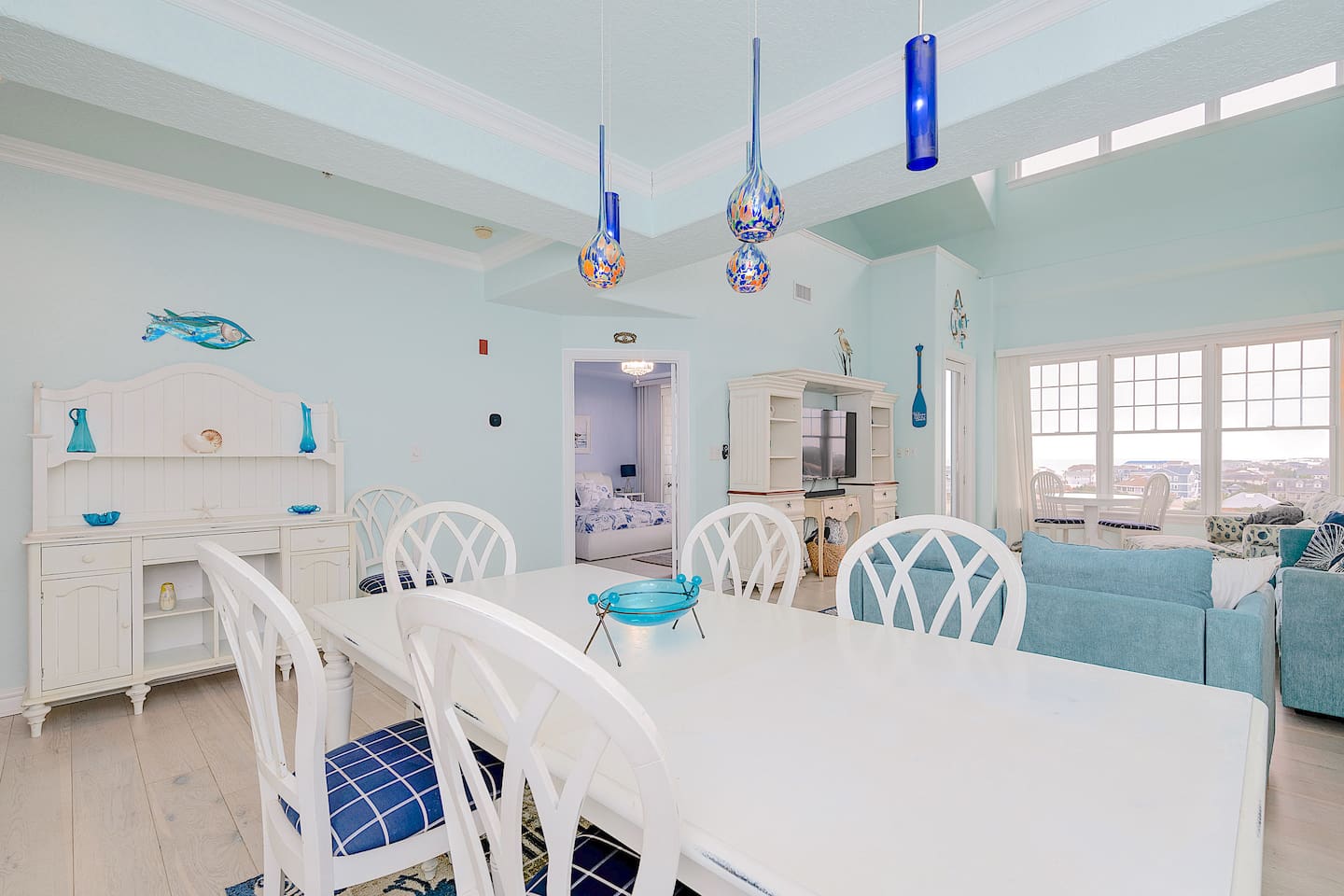 Bright and airy open-plan living and dining area with coastal decor – perfect for family meals and relaxing while enjoying ocean views through the large windows.