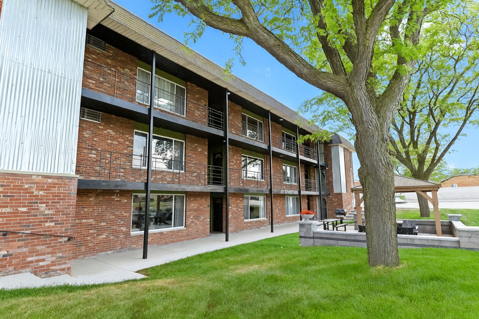 Ground-floor units with patio seating and shaded areas for relaxing outdoors.