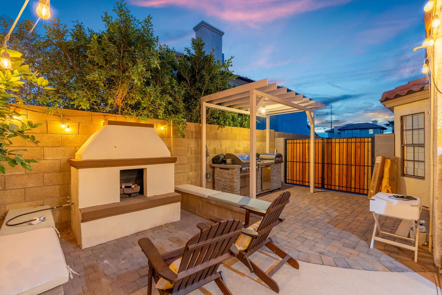 Twilight backyard with fireplace, pergola, grill, and lounge chairs—perfect for evening gatherings under the stars.