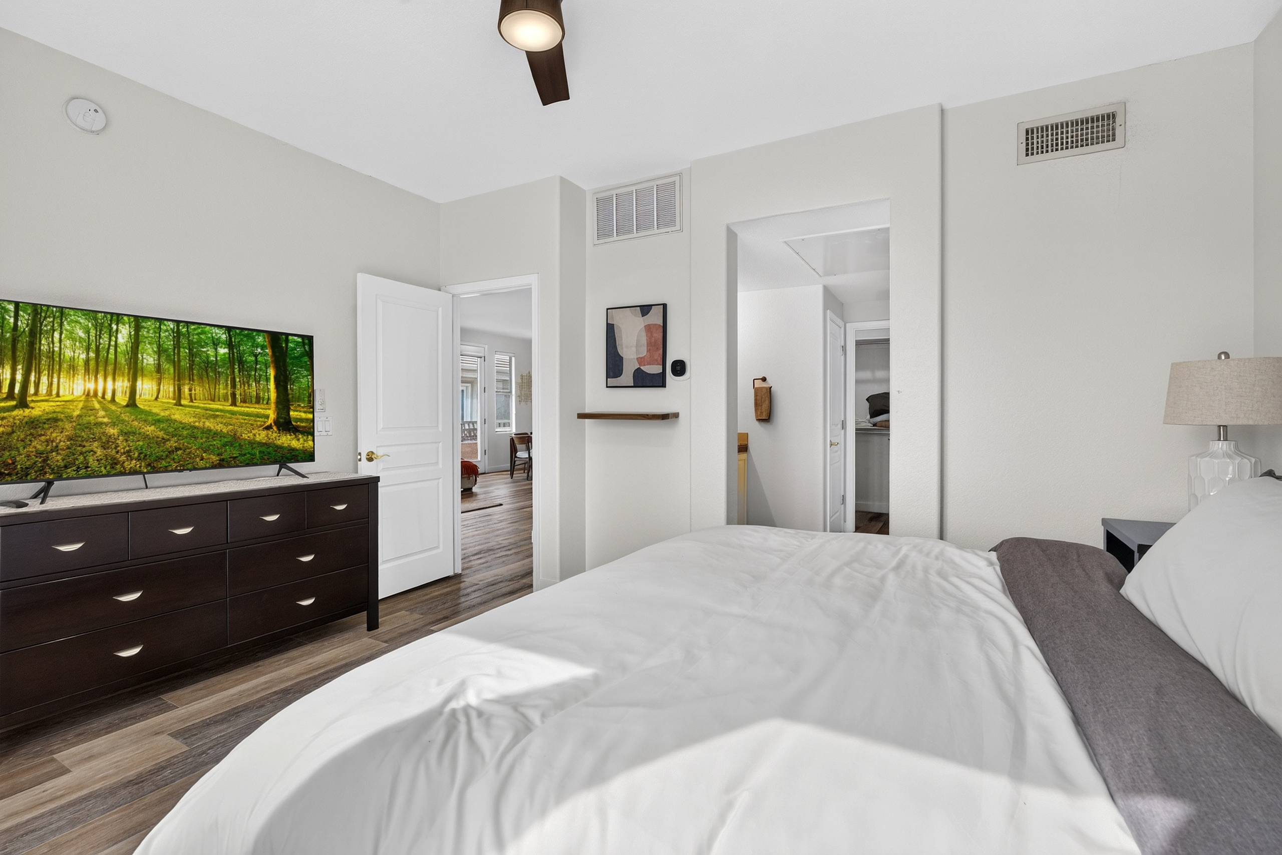 King bedroom with wall-mounted TV, dresser storage, and easy access to the nearby bathroom.