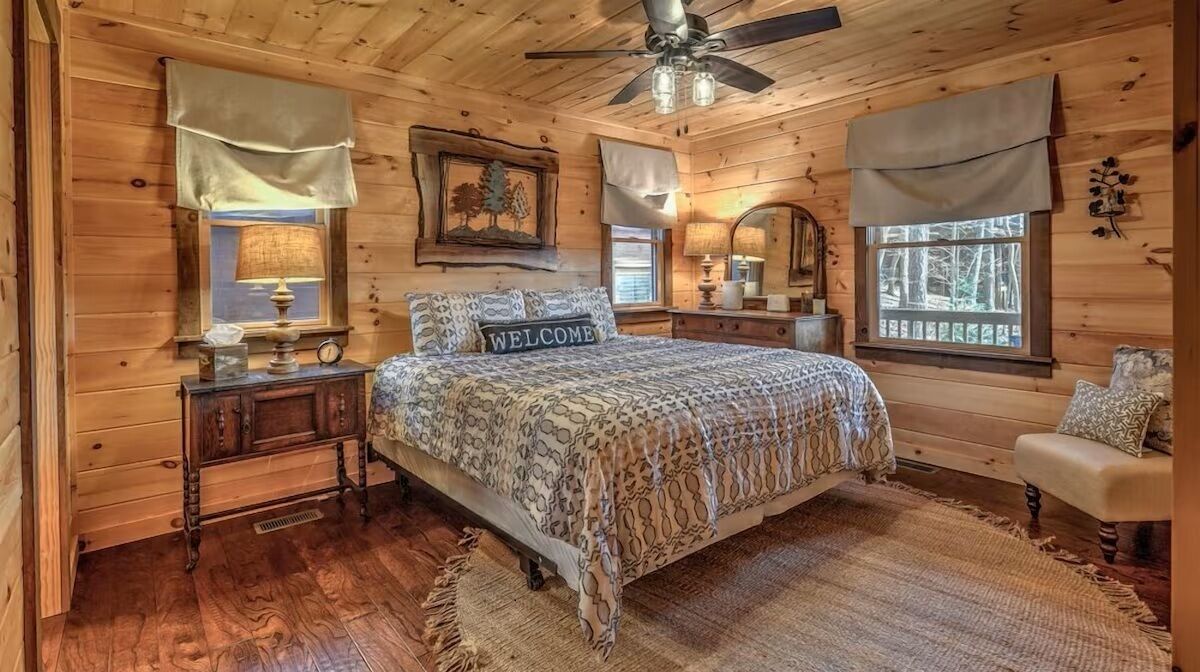 Cozy guest bedroom with warm wood finishes, comfortable king bed, and tranquil forest views - designed for rest and relaxation after a day in the mountains.