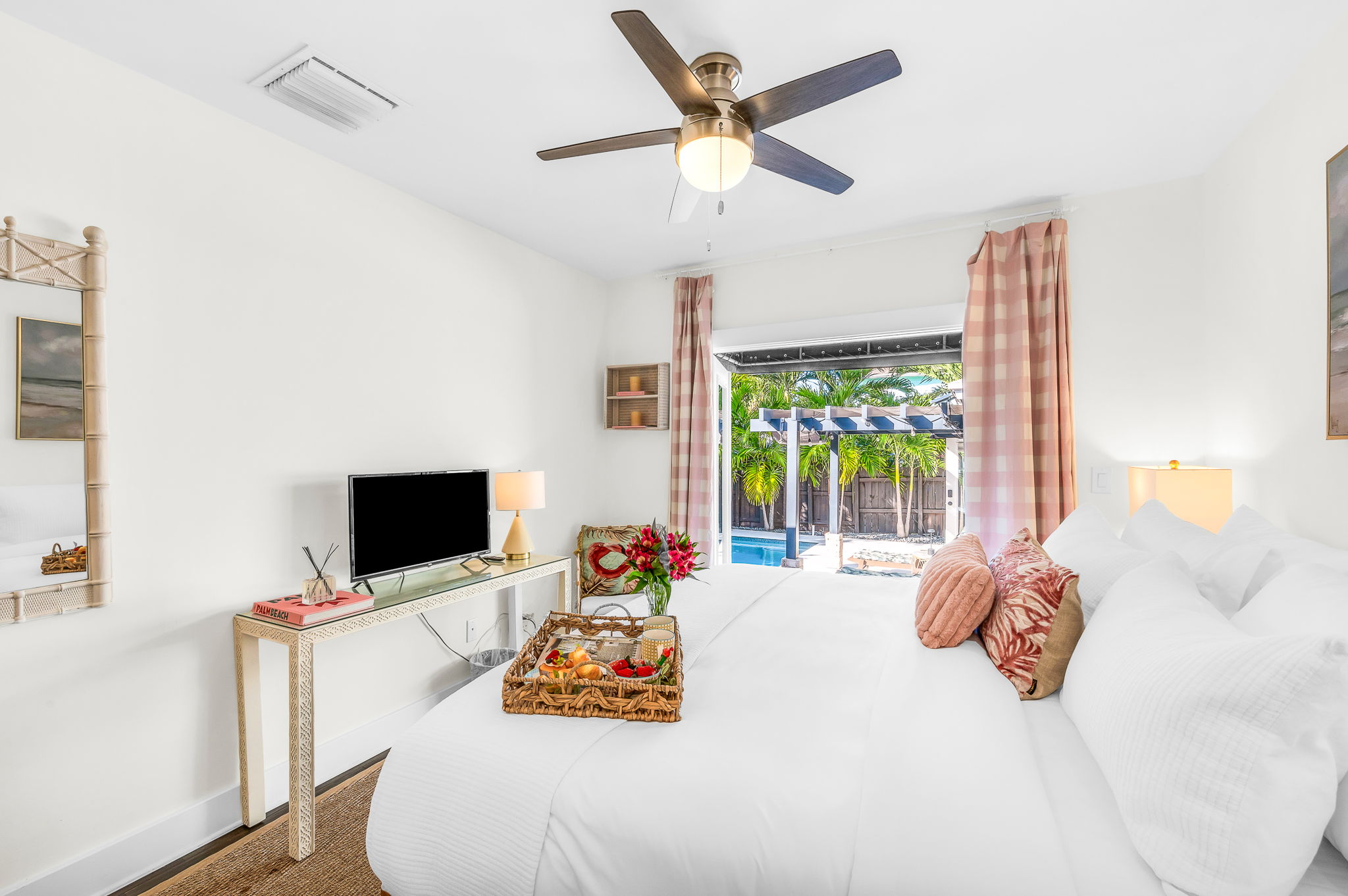 Serene king primary suite featuring a smart TV, private en-suite bathroom, and elegant French doors that open directly to the pool—perfect for seamless indoor-outdoor living and relaxing mornings or evenings.