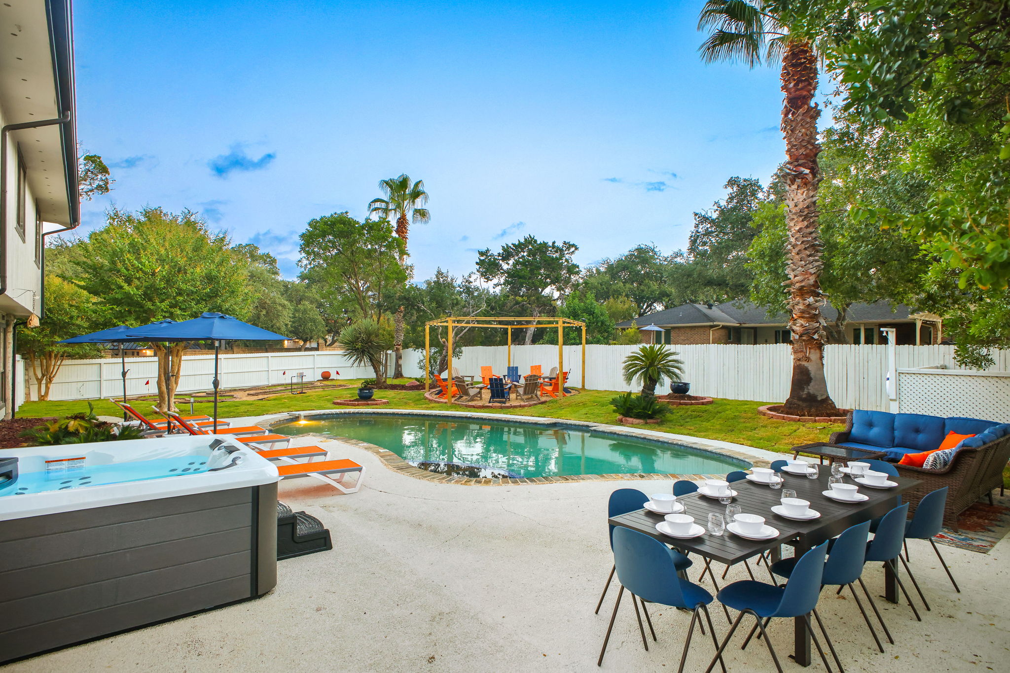 The expansive patio features a hot tub, outdoor dining for 10, and poolside loungers perfect for soaking up the sun.