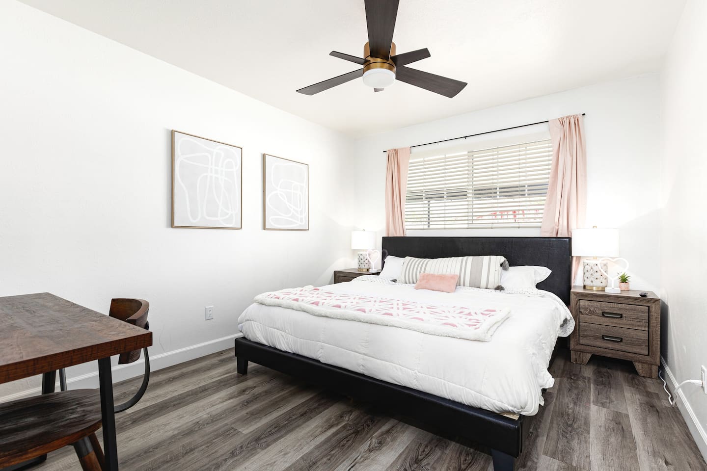 Unwind in this stylish king bedroom featuring soft blush accents, blackout curtains, and natural light streaming through the window.

