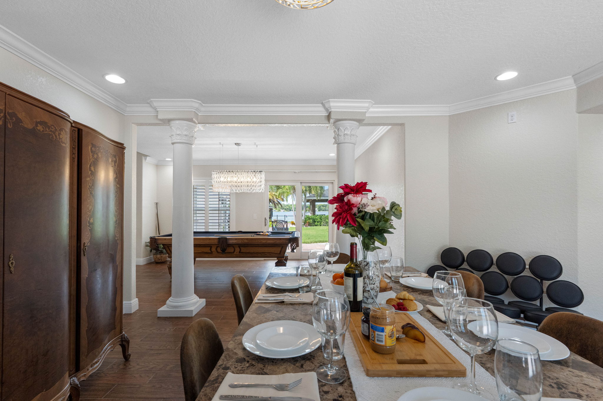 A blend of traditional elements—like decorative columns and antique-style cabinet—with modern finishes creates a versatile dining room style.