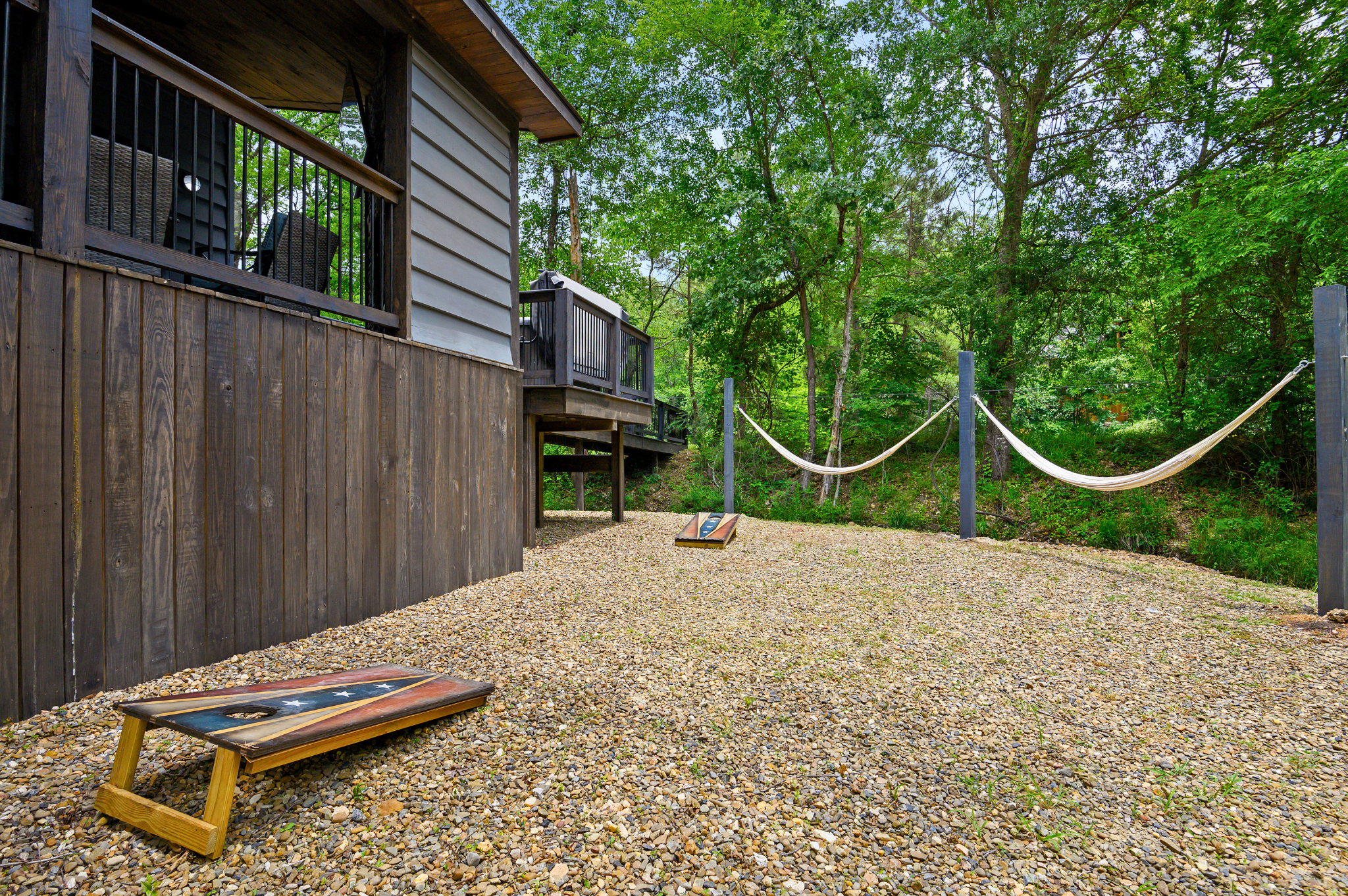 A fun backyard setup with hammocks and a cornhole game, perfect for relaxation and entertainment.
