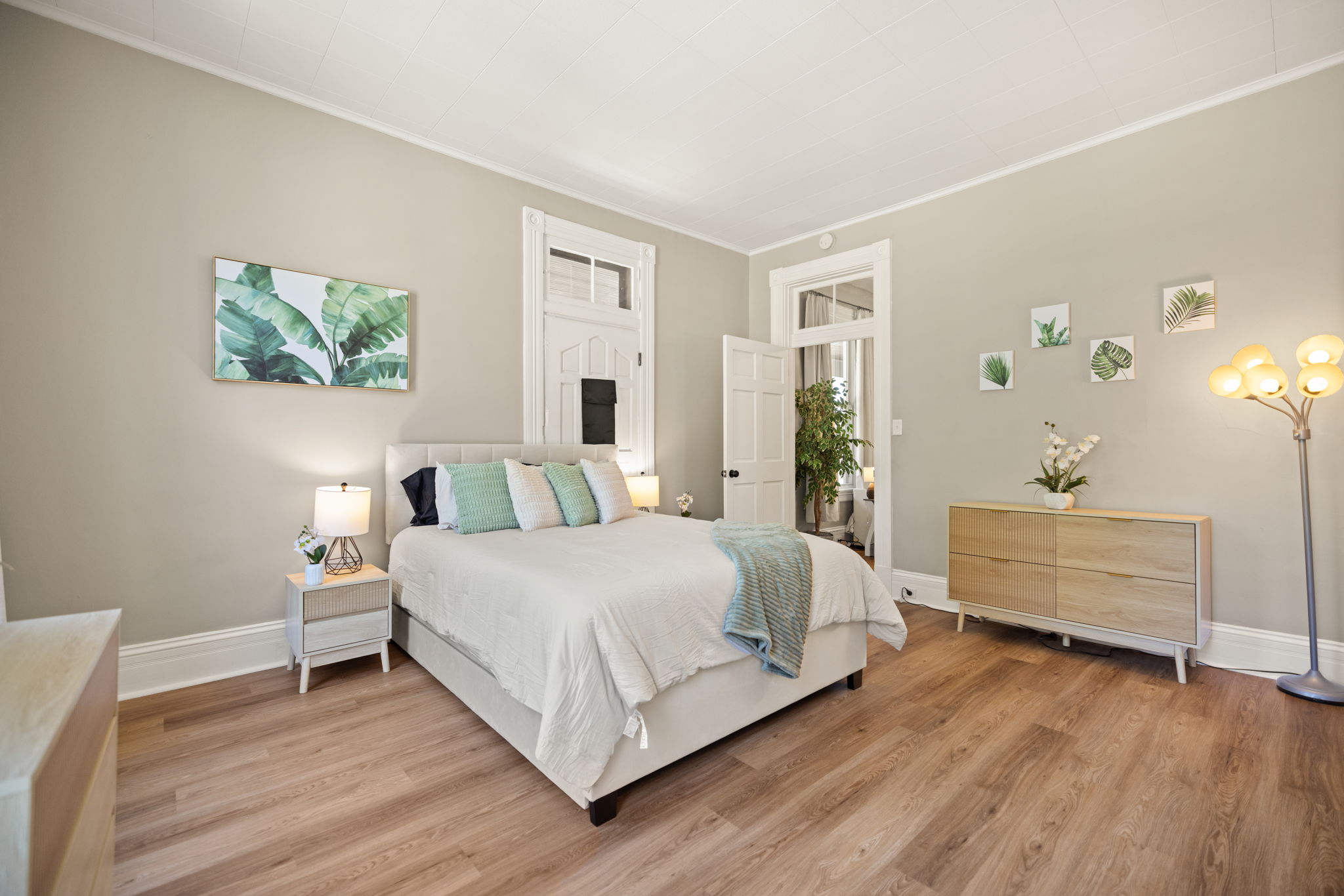 Elegantly appointed bedroom with curated teal artwork, stylish dresser, and plush bedding