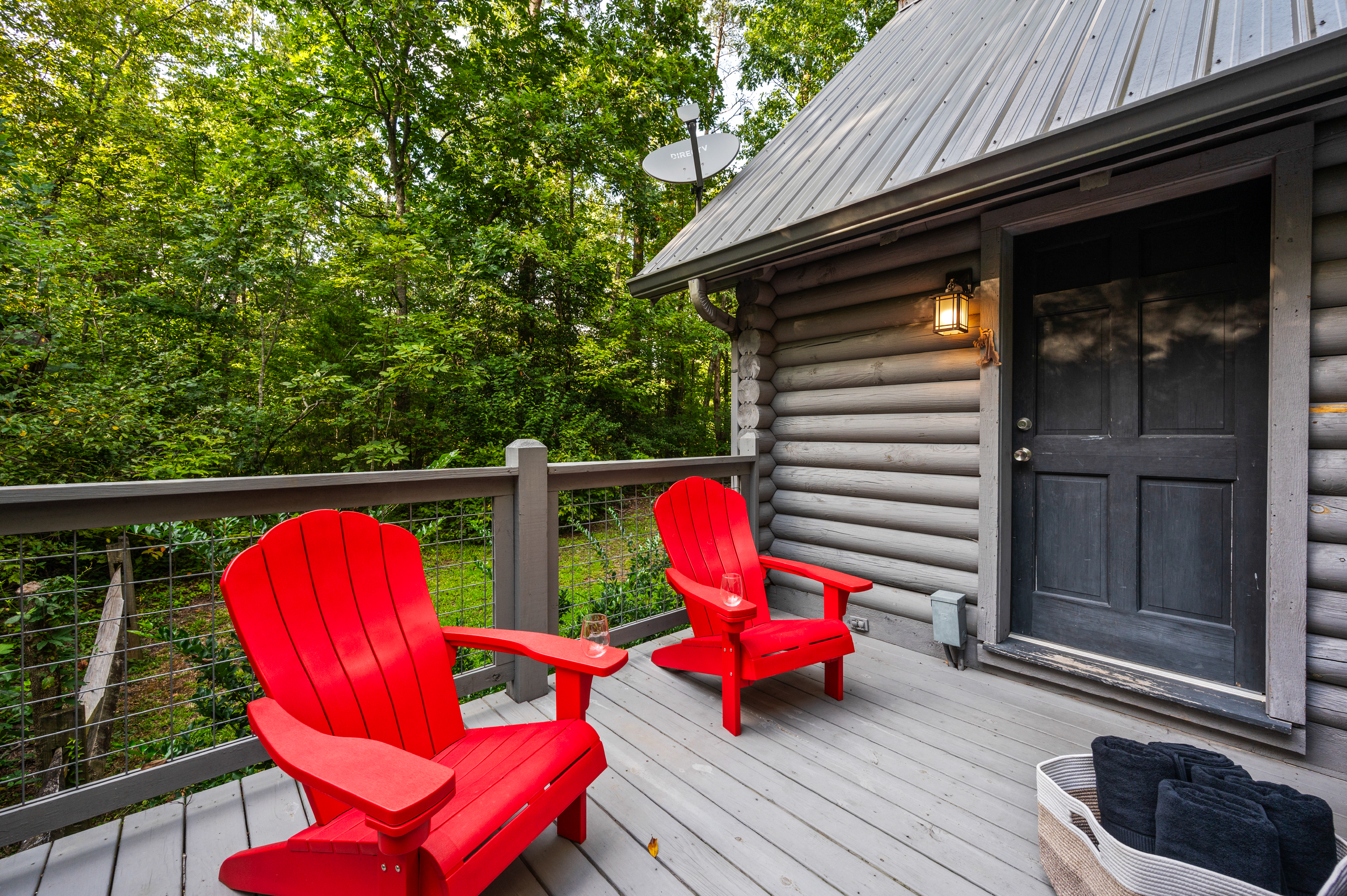Unwind on the log cabin deck, nestled in a peaceful forest setting.