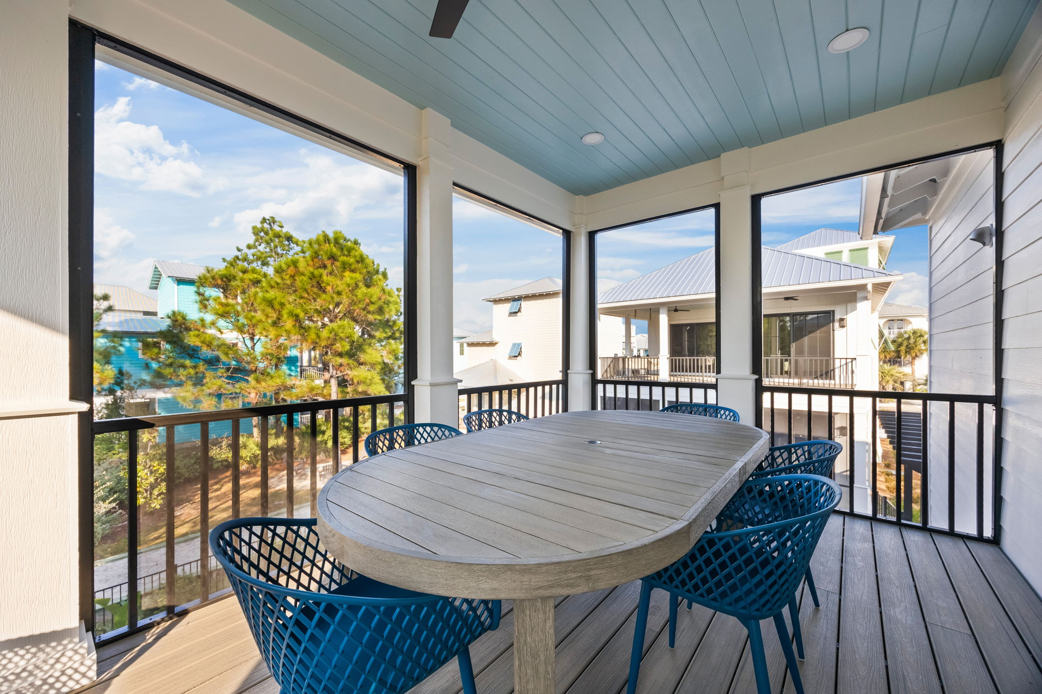 A second view of the screened upper porch shows its open, airy feel and peaceful surroundings. Enjoy dining with views of the pool and neighboring porches, where groups can easily connect and unwind together.