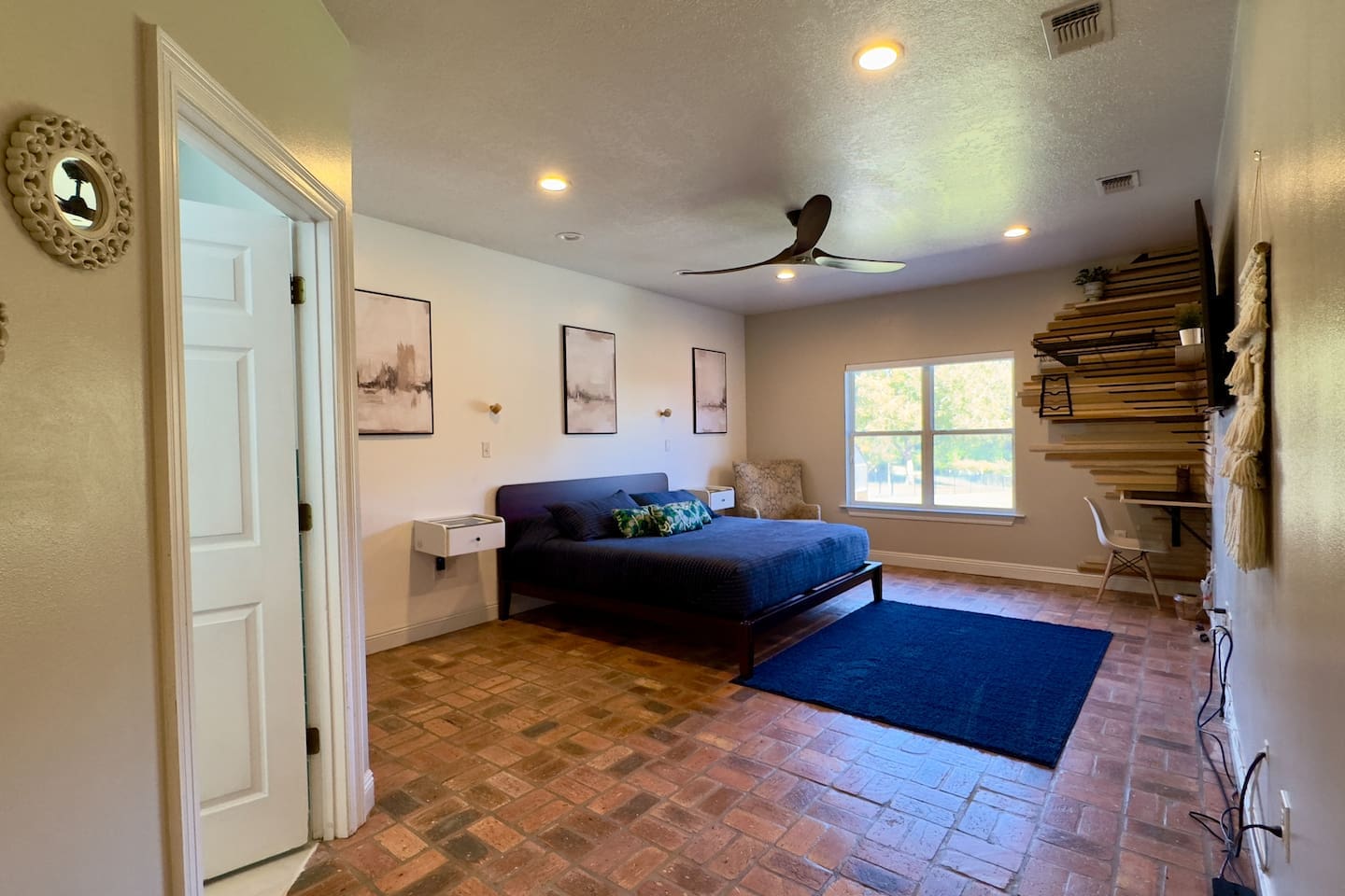 A large bed with navy blue bedding and a dark frame anchors the room in sleek simplicity.
