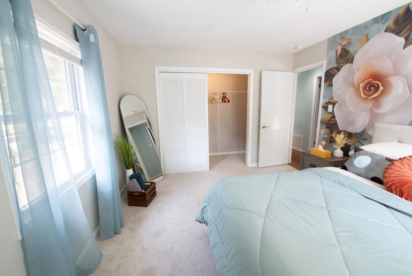 Serene guest room with soft tones, full-length mirror, and great natural light — a simple, relaxing place to unwind.