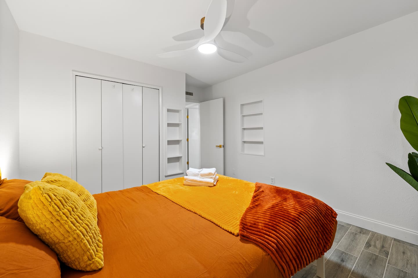 Bright bedroom with cozy orange bedding, blackout curtains, and ample closet space—perfect for restful nights and relaxed mornings.