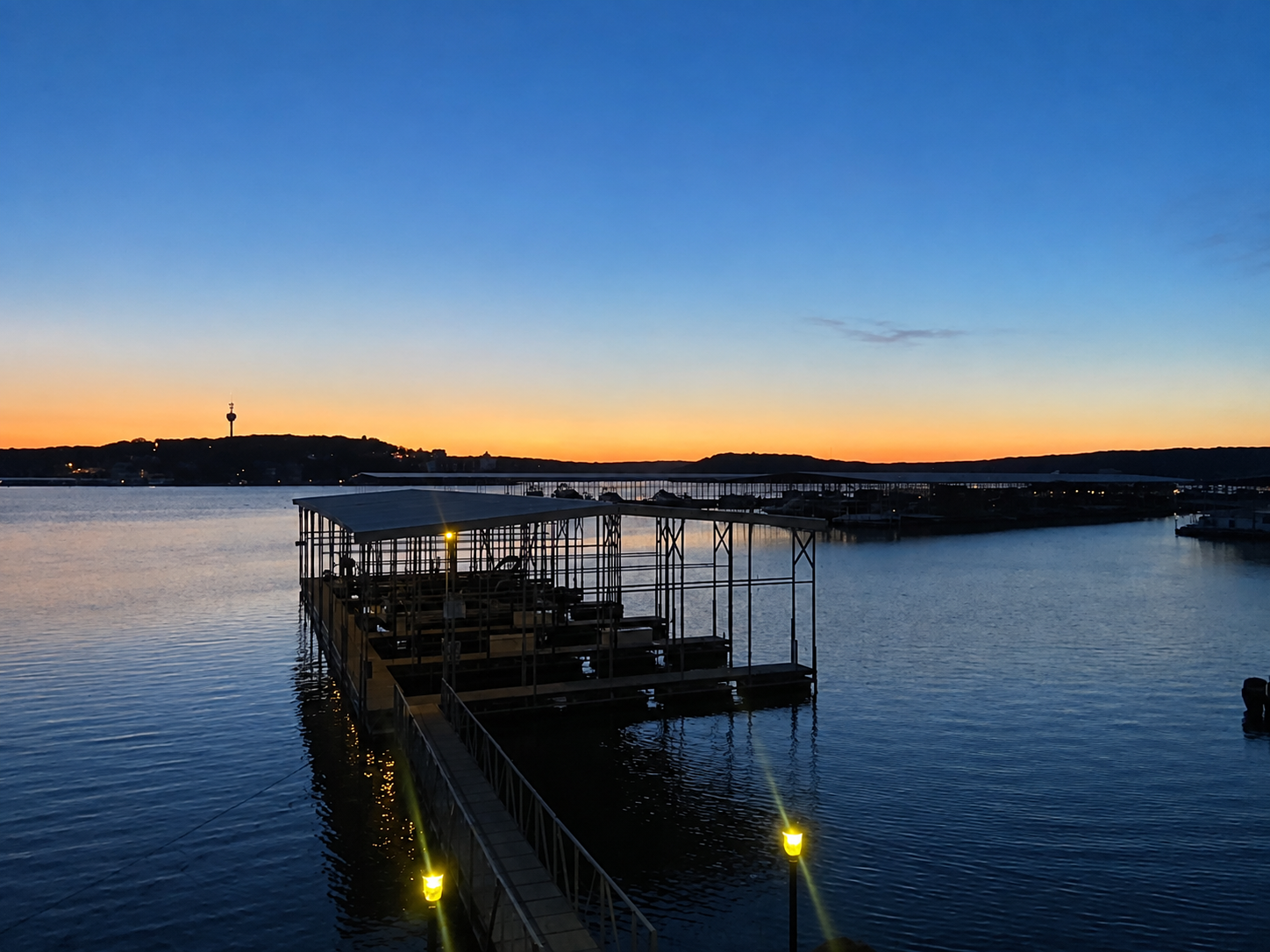 Illuminated dock extending over the water at sunset
