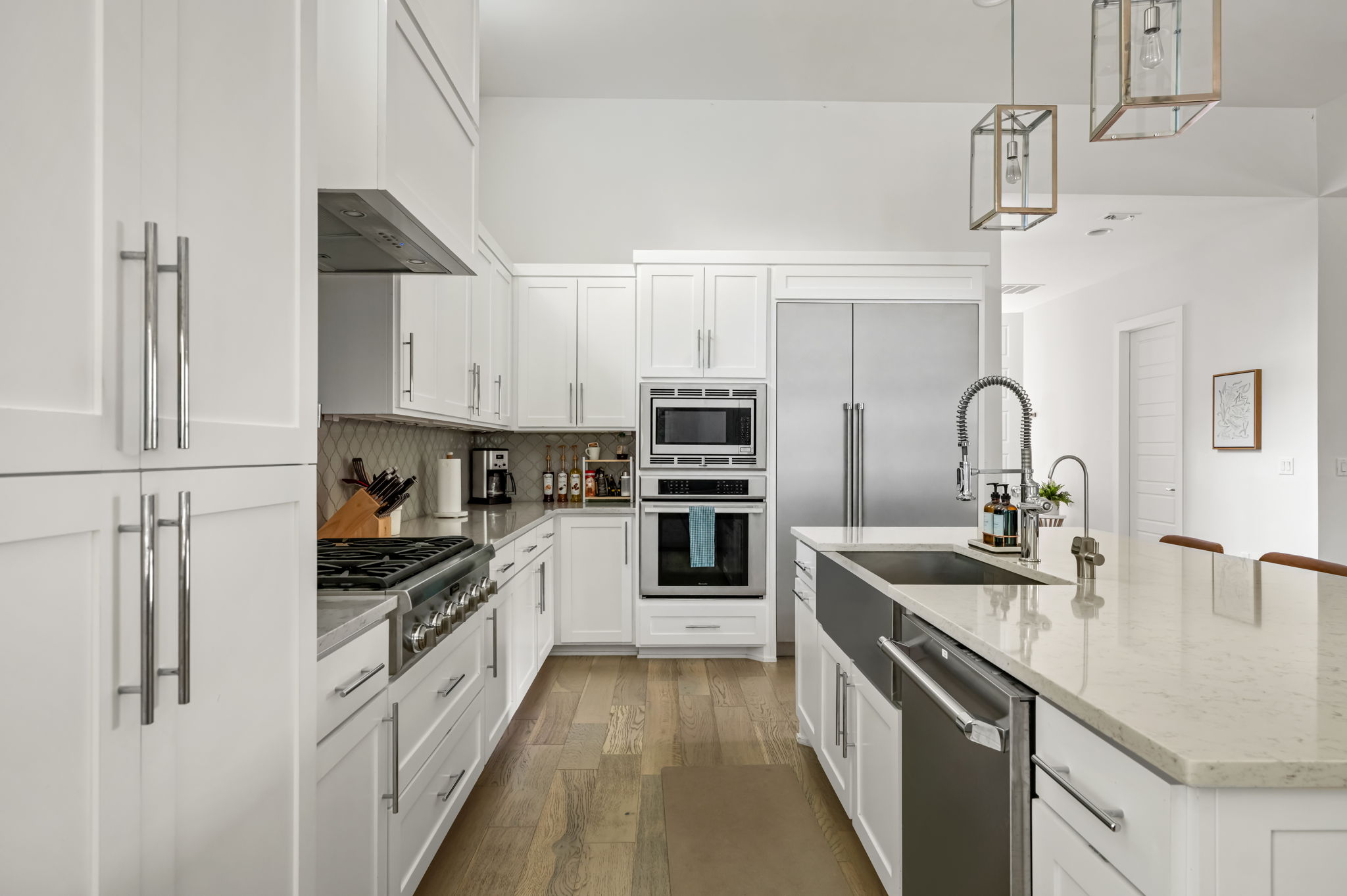 Sleek kitchen featuring double wall ovens, custom white cabinetry, and a large prep sink — thoughtfully equipped for home cooks of all levels.