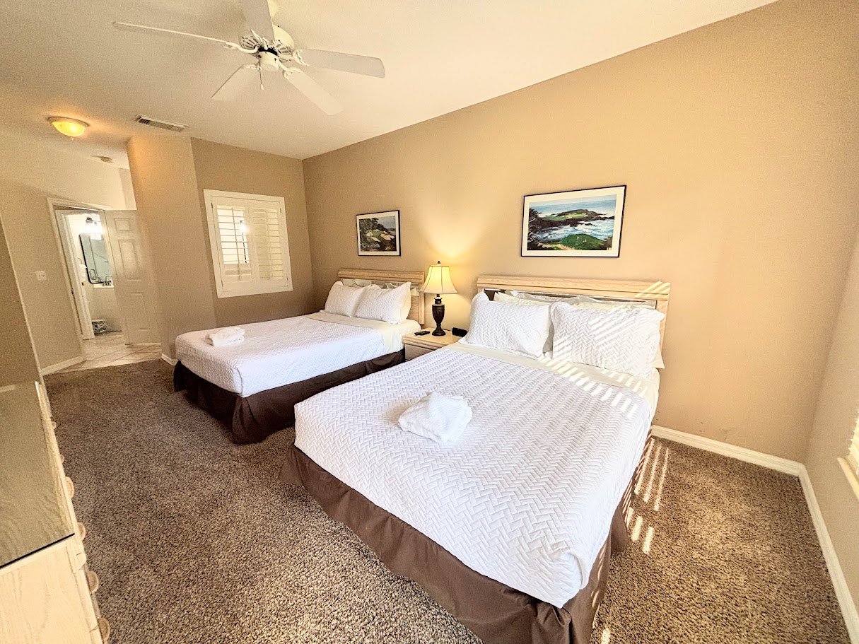 Bright bedroom featuring two beds, bedside lighting, and convenient access to the bathroom area.