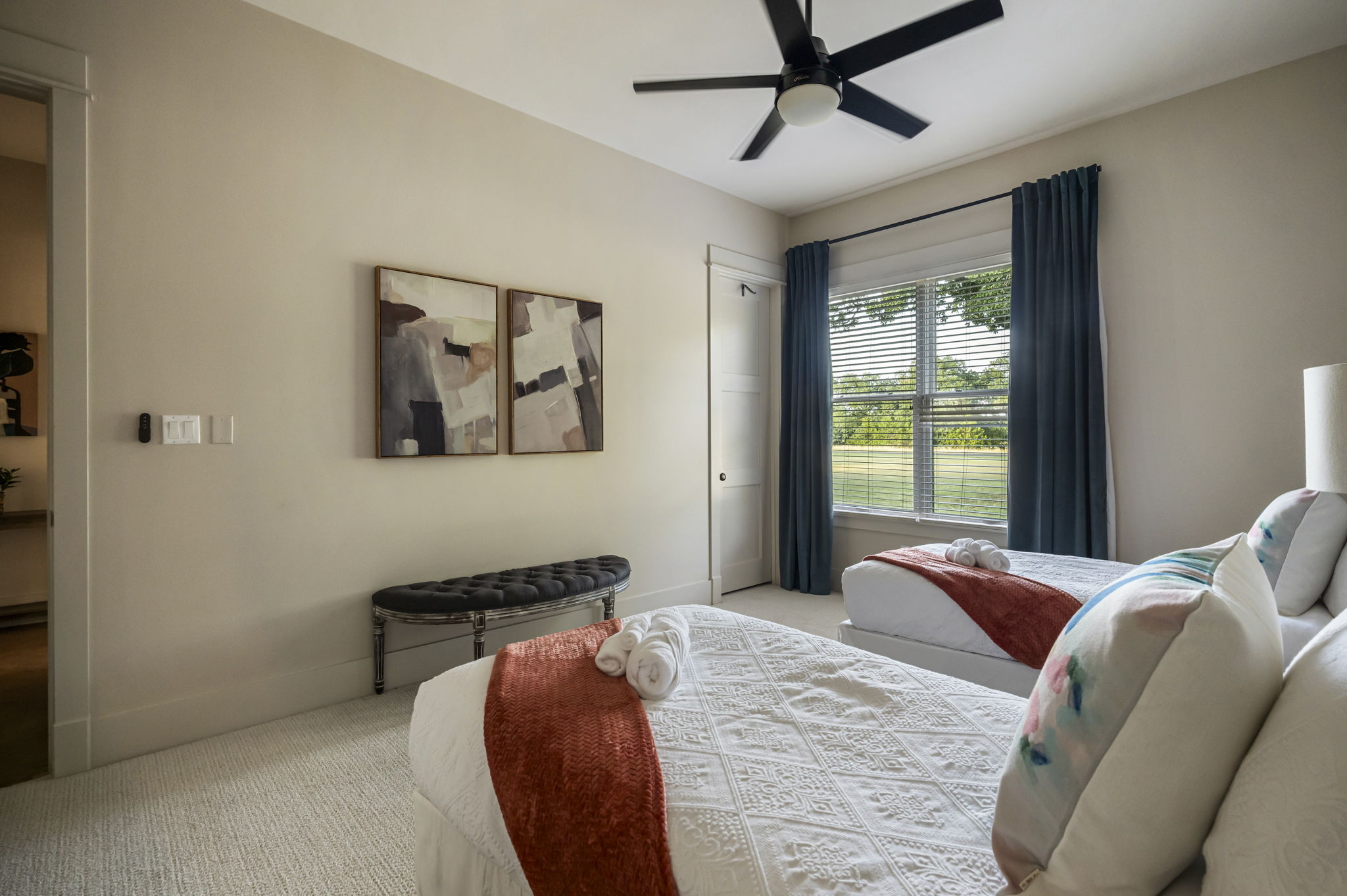 Bright and comfortable with two twin beds, a ceiling fan, and a lamp, making it a cozy space for family or friends.