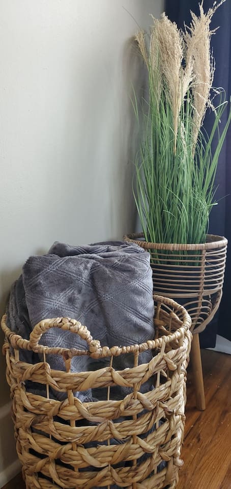 Charming corner setup with a woven basket of cozy throws and a decorative planter—adding warmth and natural texture to the space.
