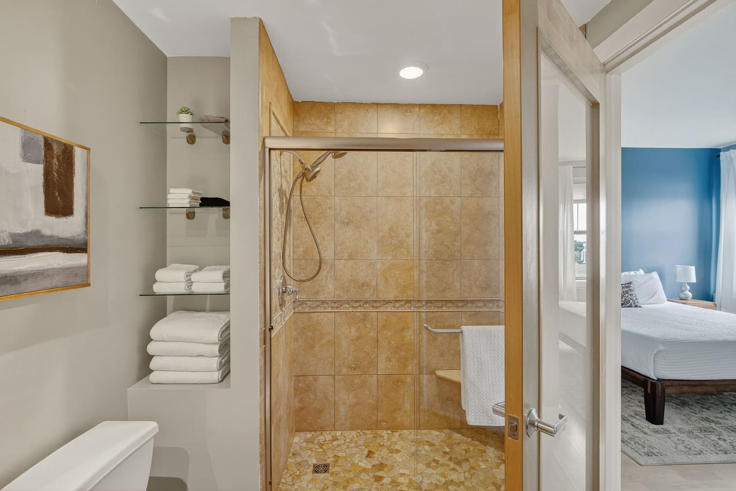Spacious walk-in shower with stone tile, glass door, and rainfall showerhead. Complete with fresh towels and built-in shelving, it’s the perfect retreat to recharge after exploring downtown Des Moines.