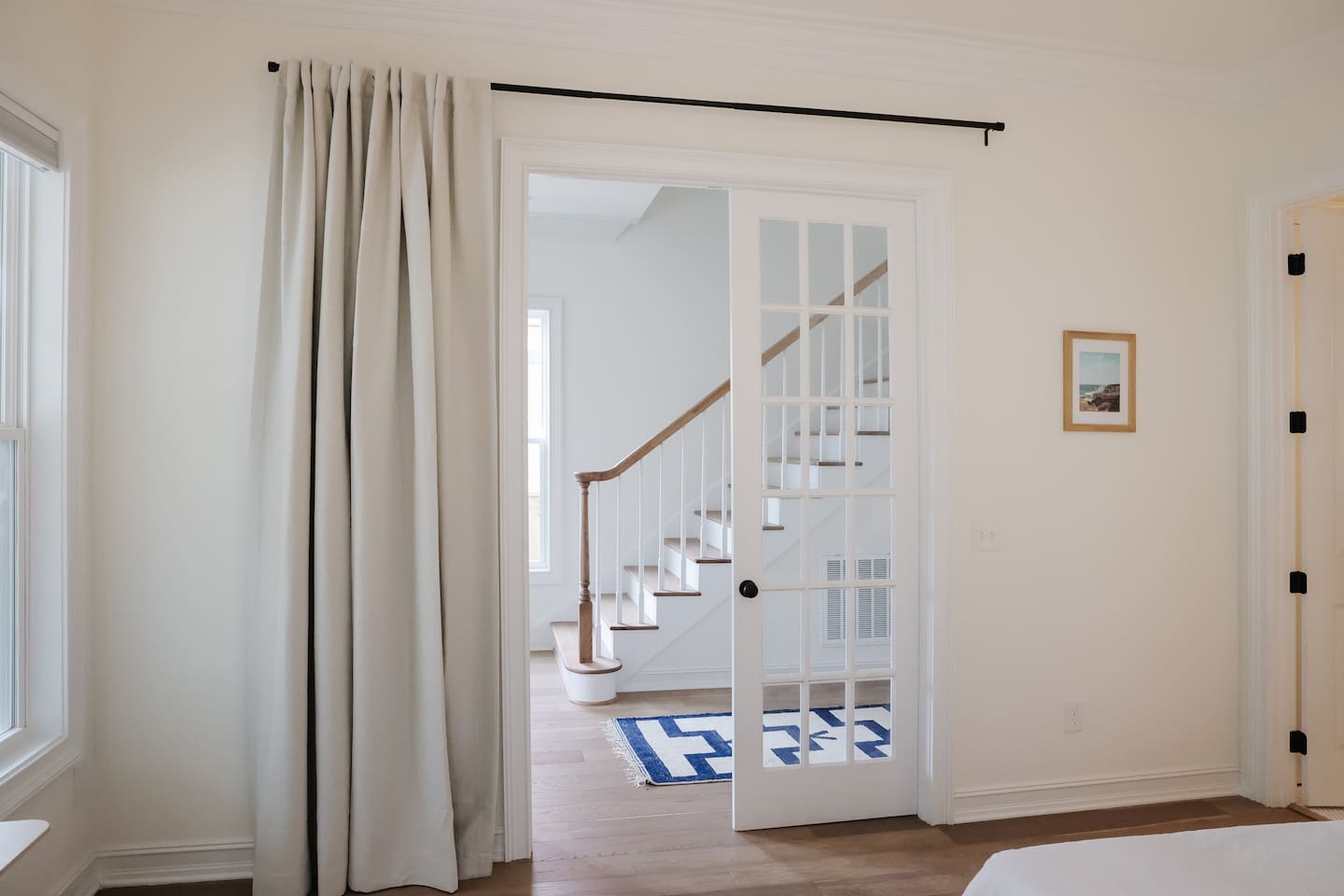 The downstairs bedroom is off of the foyer hallway with glass french doors. Thick blackout curtains provide privacy to room guests.