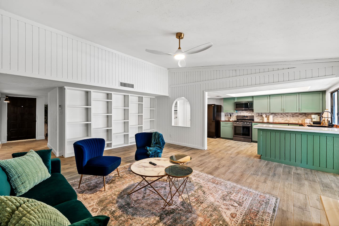 Chic and cozy living room with vibrant velvet seating, statement decor, and open shelving—perfect for relaxing or hosting in style.