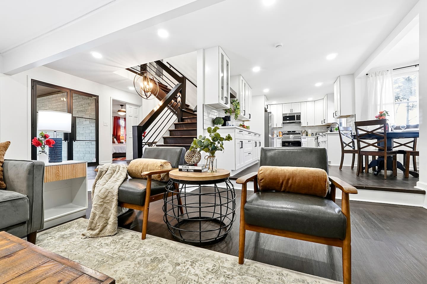 Warm and welcoming living room with two comfortable couches, two chairs, indoor plants, a cozy fireplace, and a TV powered by Google TV. Conveniently located as you walk through the front door and straight ahead from the primary side entrance. 