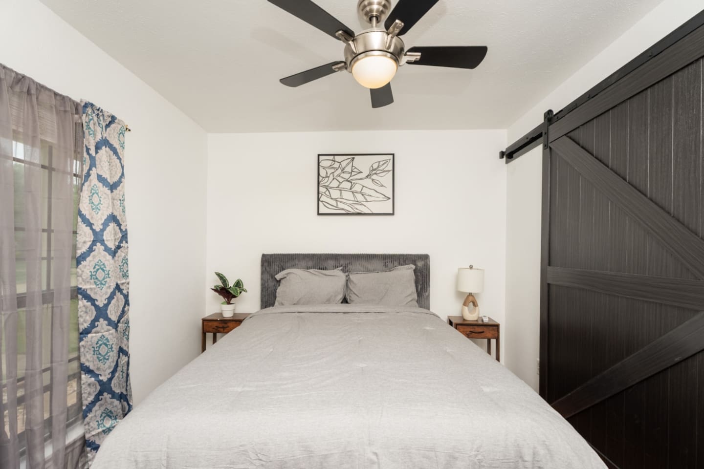Bedroom with queen bed and statement patterned curtains.