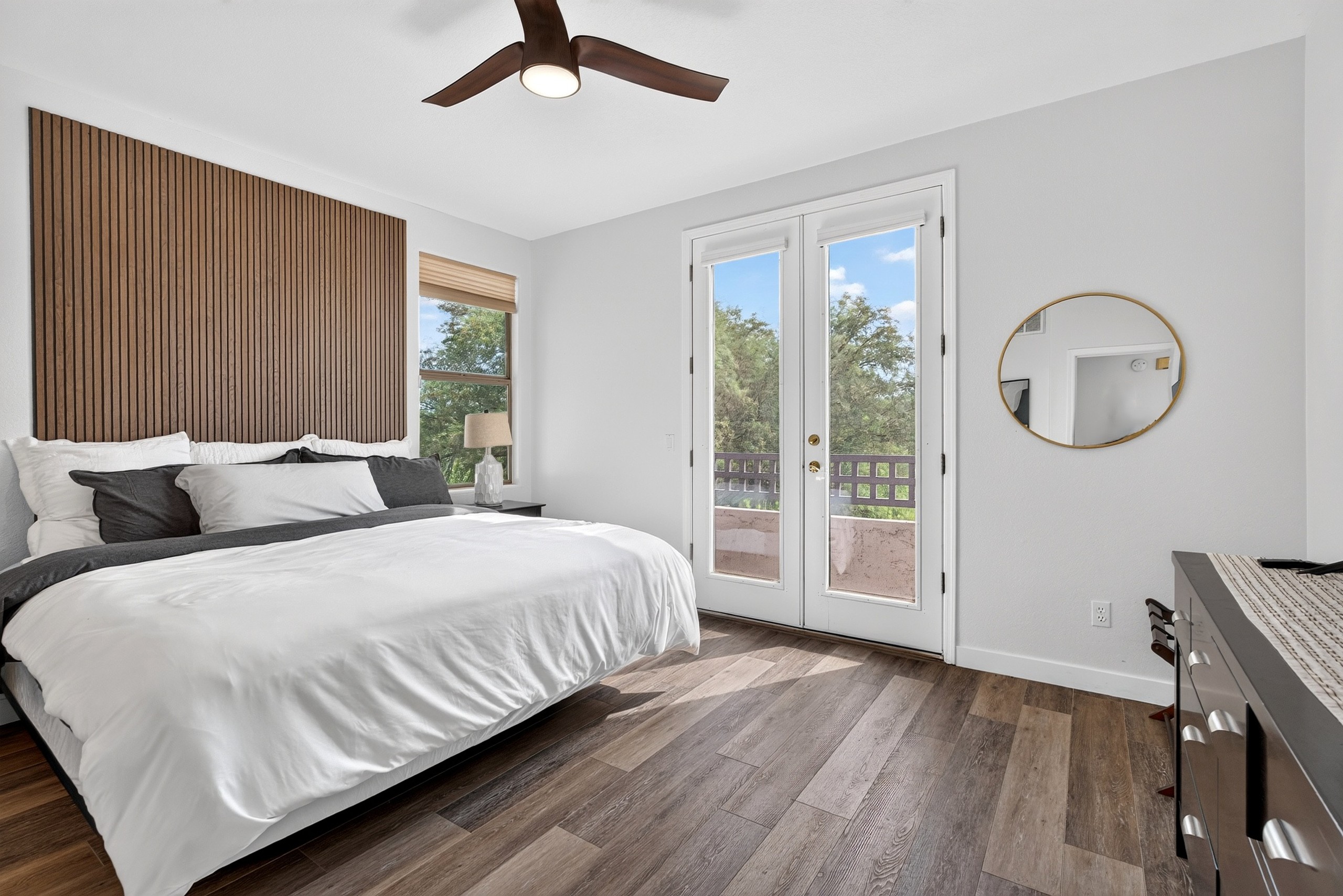 King bedroom with soft layered bedding, bedside lighting, and private balcony access for a comfortable stay.
