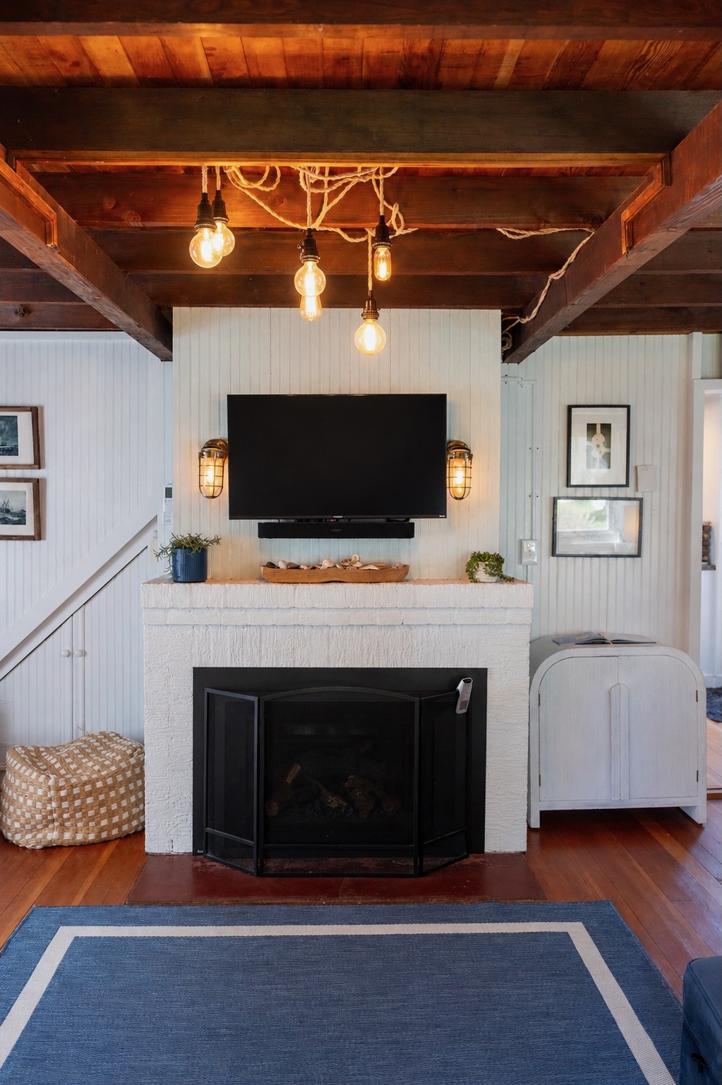 Beadboard-lined walls and exposed beams bring cozy cottage charm to this inviting living room, complete with a smart TV for modern comfort.