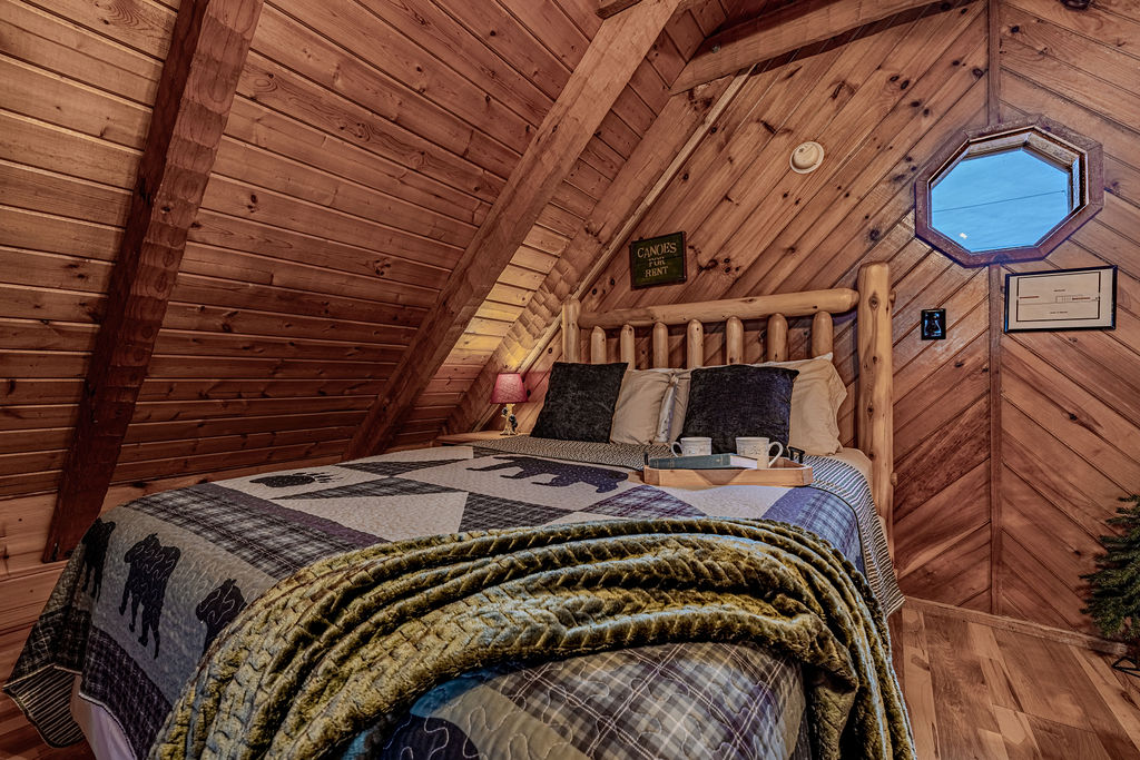 Wake up to mountain light in this snug loft bedroom with a rustic log bed. 