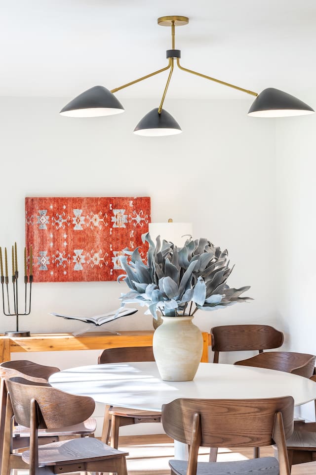 Dining room detail featuring curated décor, warm wood tones, and statement art. Thoughtful styling and natural light create an inviting atmosphere for shared meals and relaxed gatherings for up to 8.