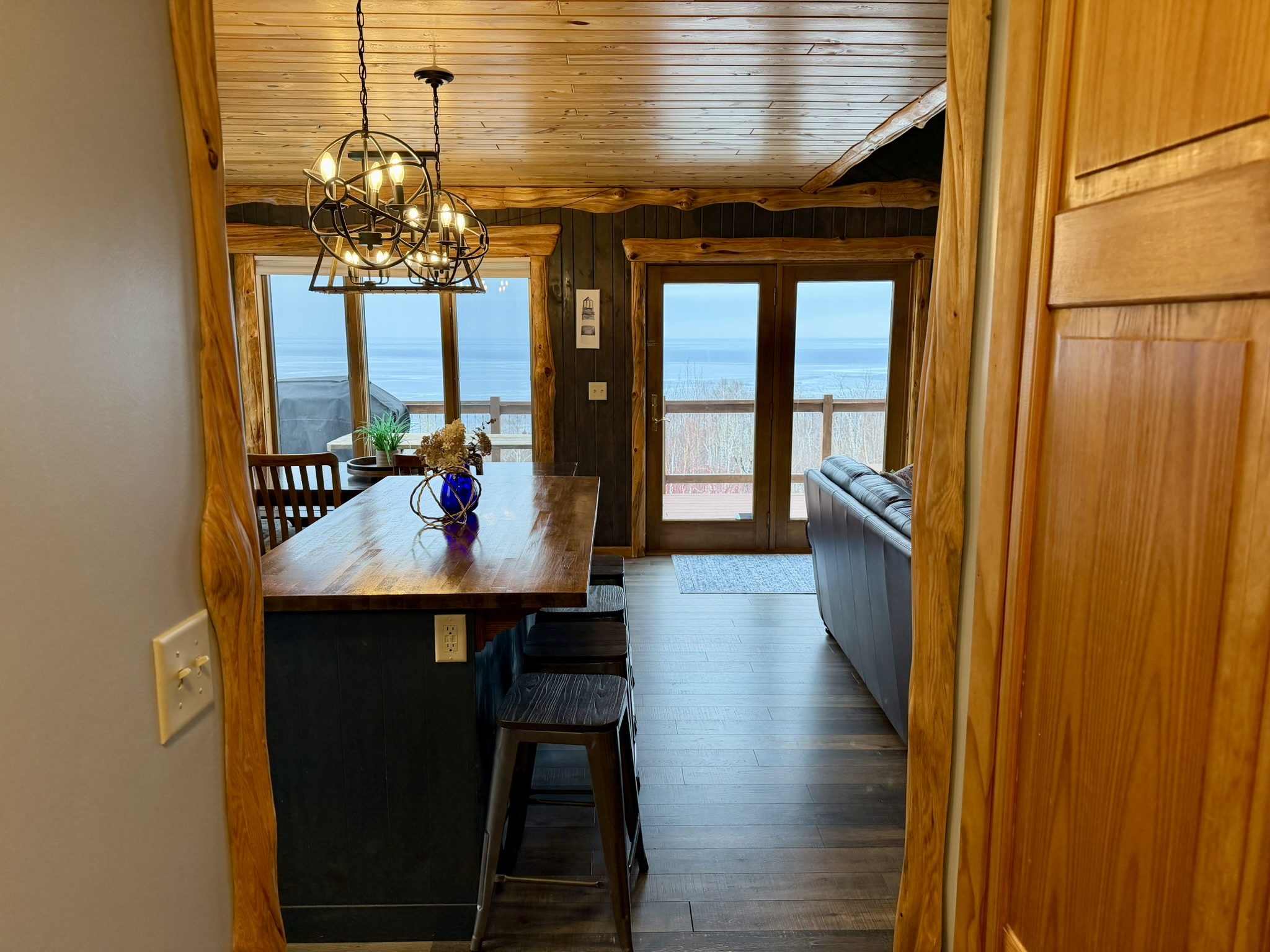 Stepping into the main room Lake Superior view hits you with open living room + kitchen with the island just coming into view. Bright windows, and a welcoming layout made for relaxing together.