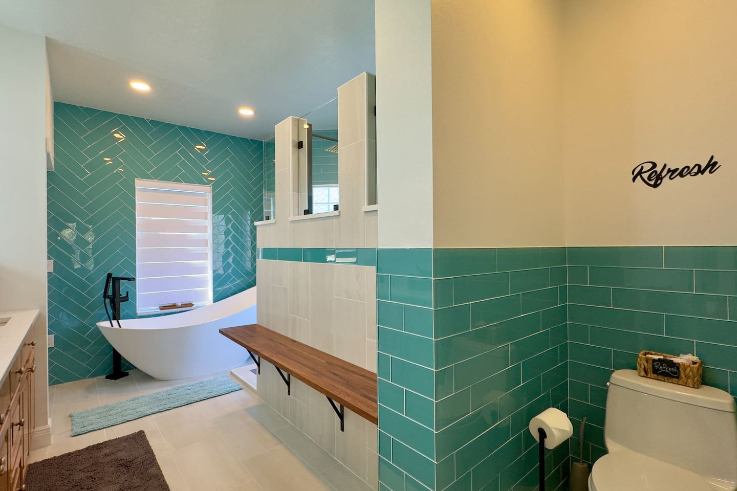A freestanding white bathtub set against turquoise herringbone tiles creates a vibrant focal point.