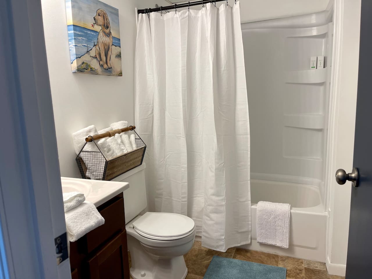 Fresh, cheerful bathroom with full tub/shower combo, fluffy towels, and fun coastal artwork. Clean and well-stocked, this inviting space has everything you need to feel at home—perfect for getting ready or winding down after a day of adventure.