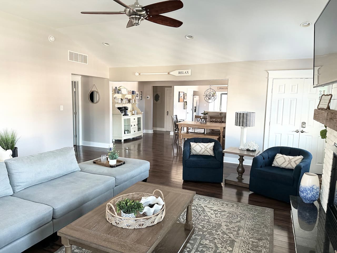 Experience the seamless flow of our open-concept living space, where the cozy seating area leads right into a charming dining nook. With neutral tones and coastal accents like the "RELAX" oar, it’s a tranquil environment designed for easy vacation living.