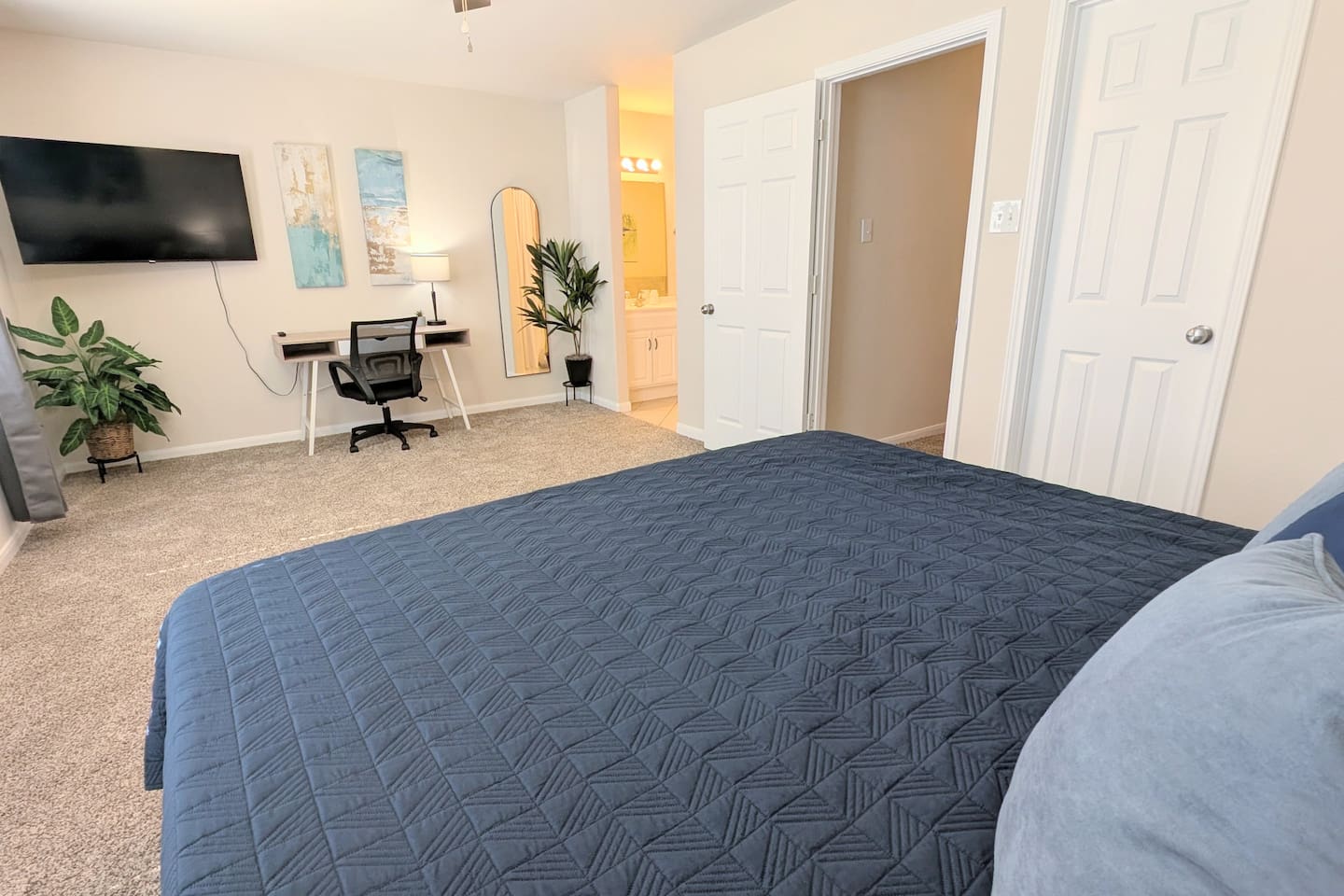 Bedroom as a 55" smart TV, dedicated work space, full-length mirror, large walk-in closet, and direct access to the en suite bathroom. 