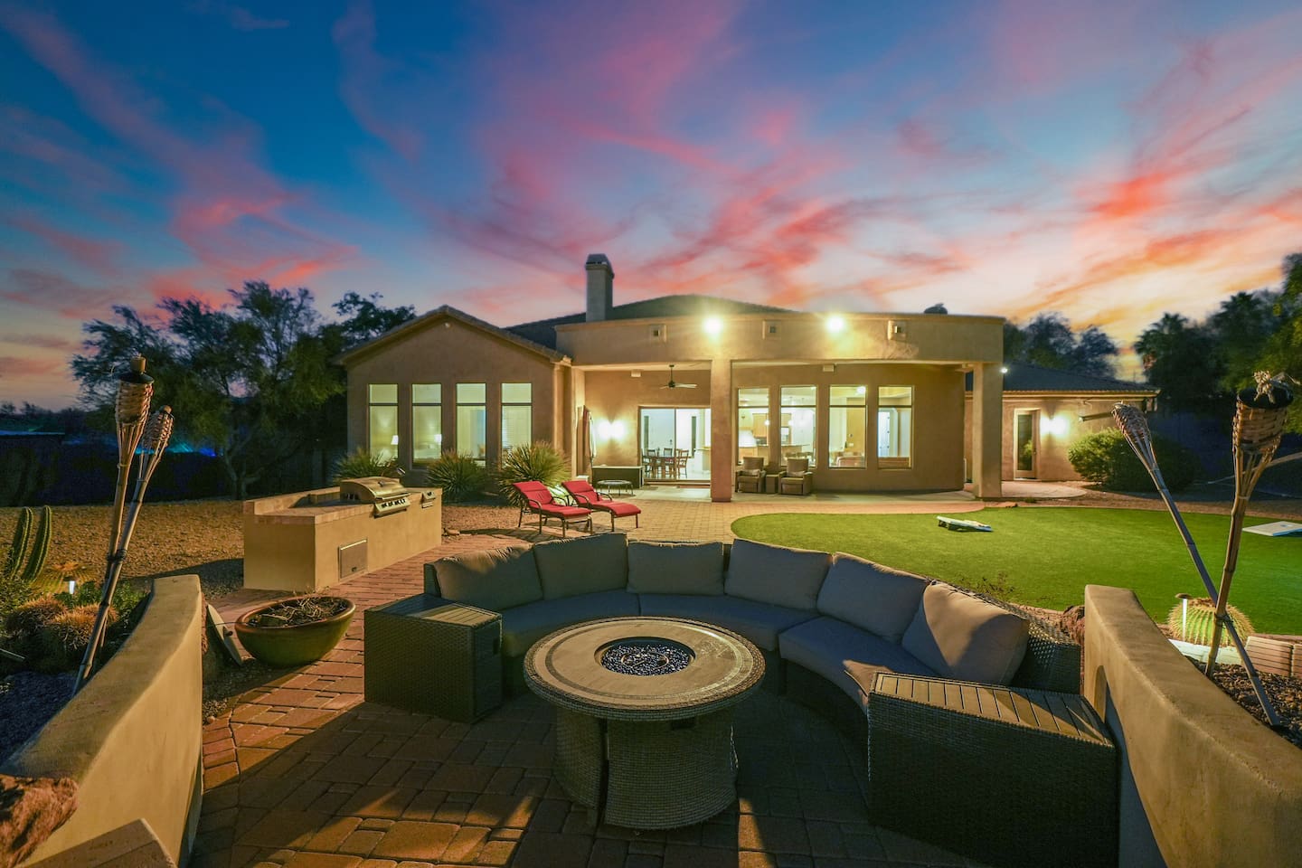 Sunset views over the backyard featuring a cozy outdoor fire pit lounge and beautifully lit patio areas.